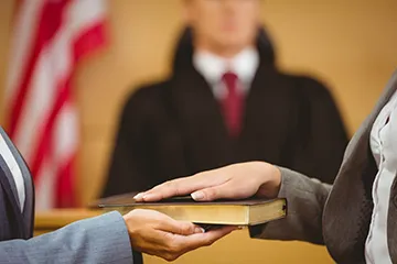 image of a court employee holding the bible for someone ready to take the witness stand